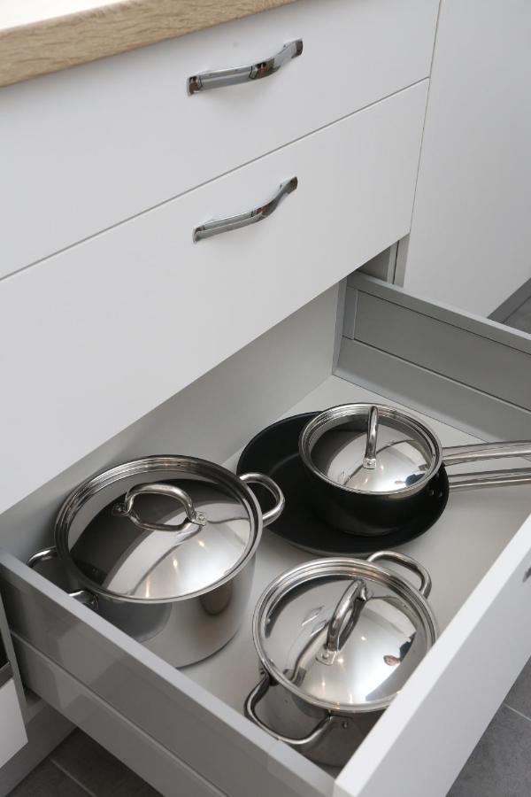 Kitchen drawer with stainless-steel pots, a saucepan and a frying pan neatly stored
