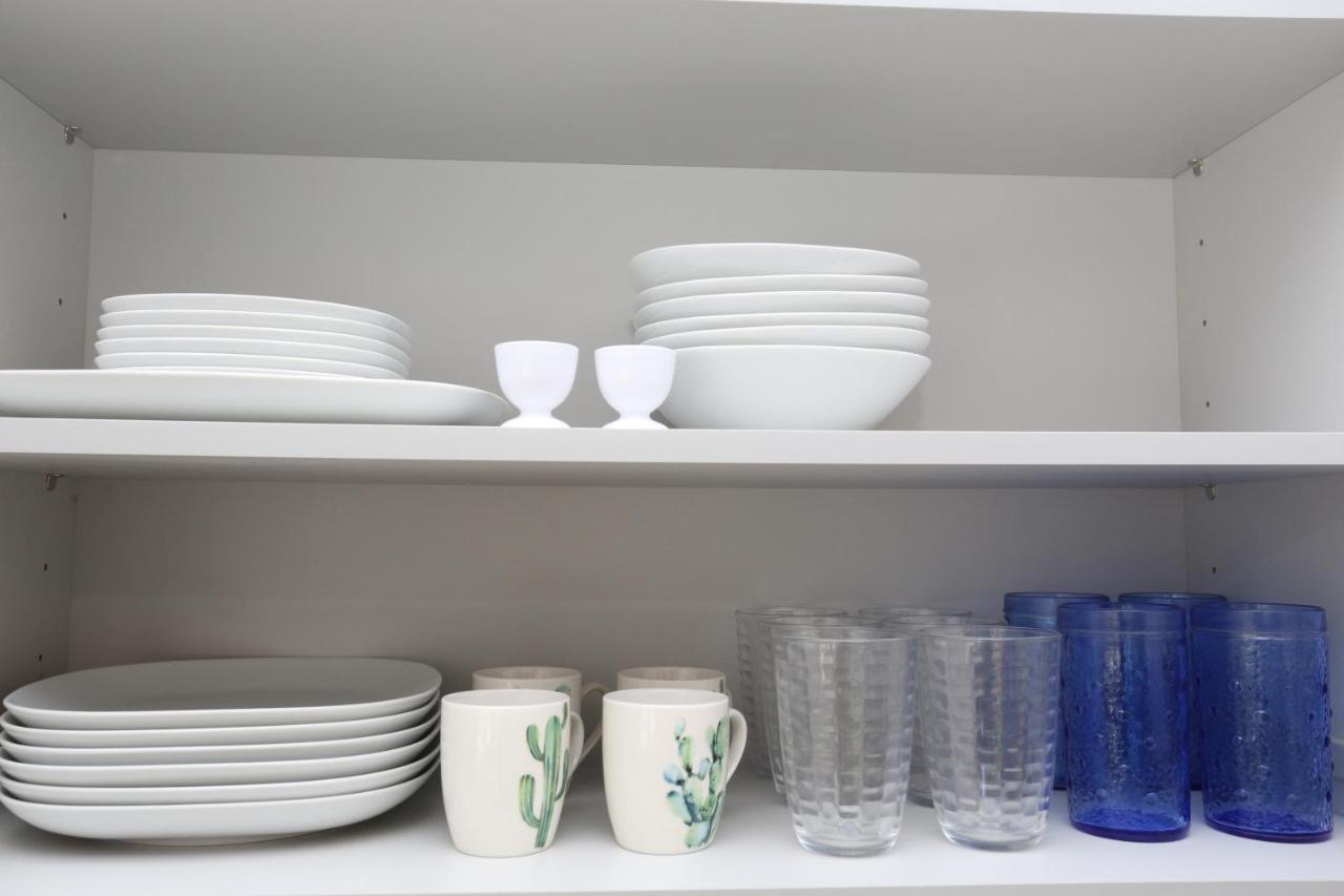 Kitchen cabinet shelves with stacked plates, glasses, and mugs