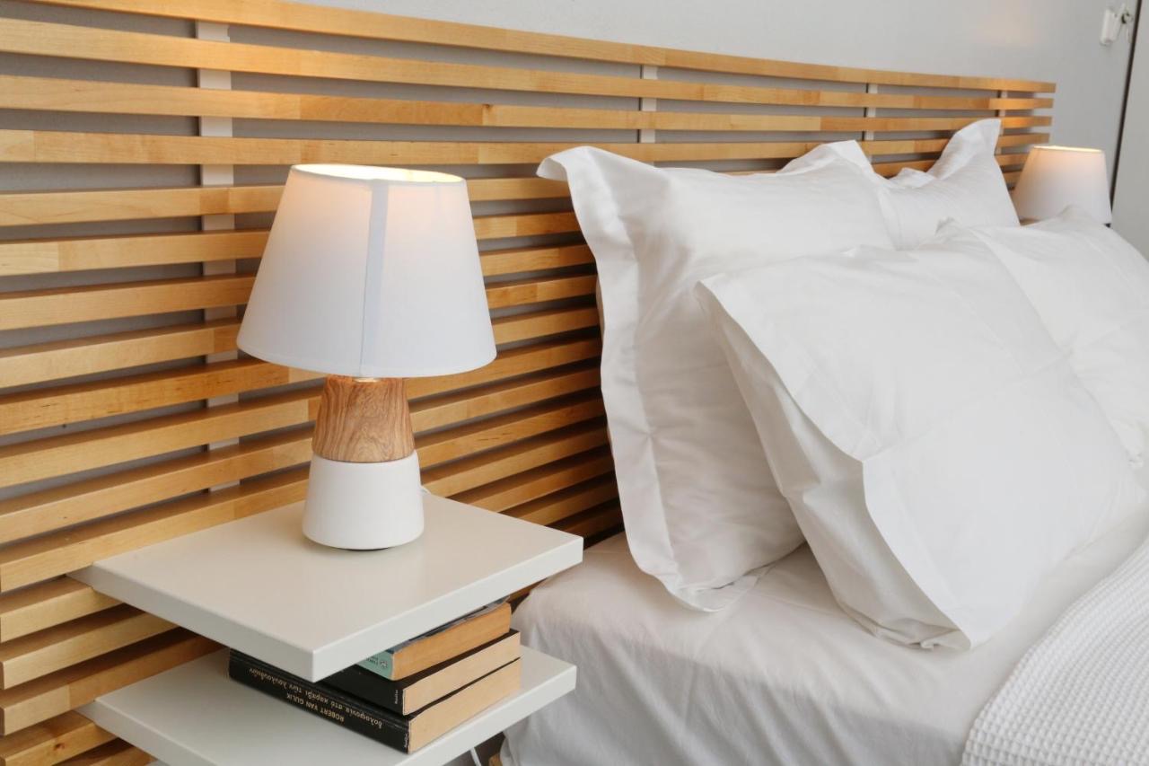 Cozy bedside detail with wooden headboard, nightstand, lamp and stacked books